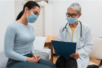Female healthcare provider wearing mask and stethoscope reviewing patient chart