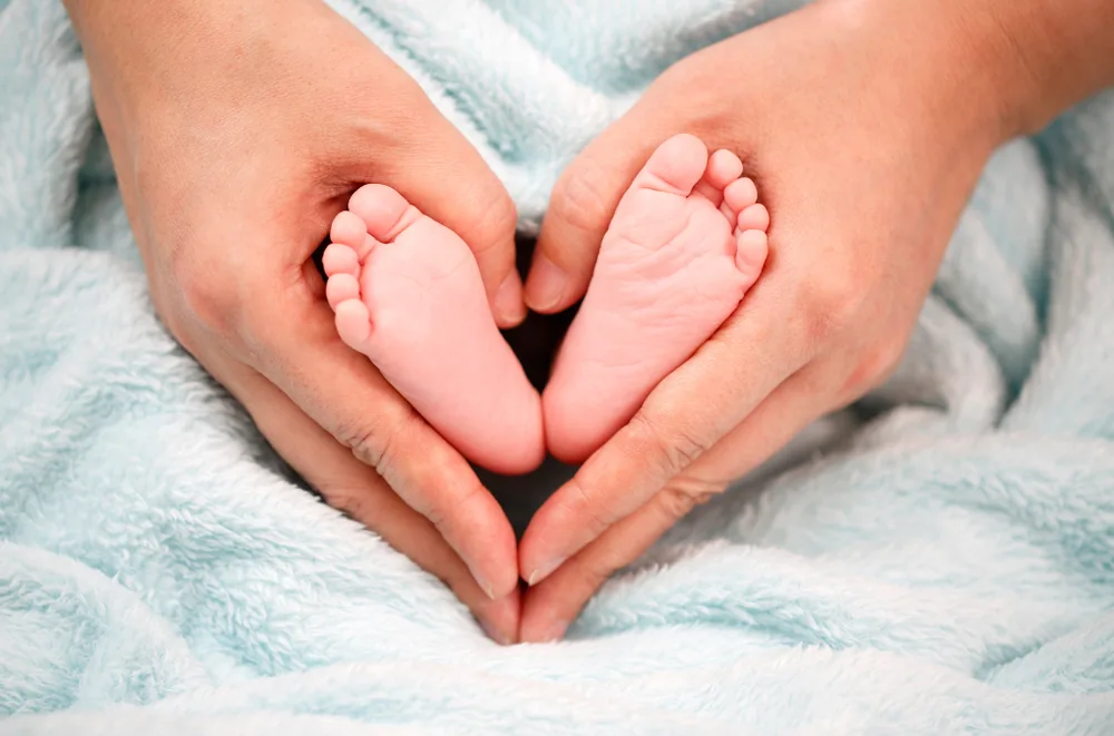 A parent's hands forming a heart around a newborn baby's feet